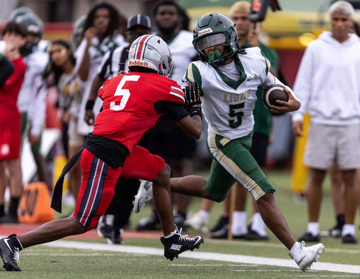 Mater Academy quarterback Nate Merrell Jr. stiff arms Doral Academy free safety Karmelo McCrea (5) during the first half of a high school football game at Doral Academy on Thursday, August 28, 2025, in Doral, Fla.
