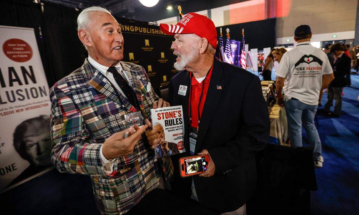Roger Stone talks with Bryan Kenady as Stone sells his book in the exhibition area during the Turning Point Action Conference at the Palm Beach County Convention Center in West Palm Beach, Florida, on Saturday, July 15, 2023.