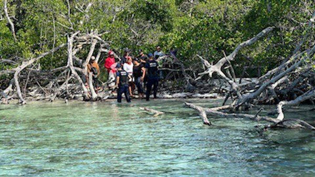 Federal officials approach Cuban migrants on an uninhabited island about 20 miles west of Key West Tuesday, June 14, 2022.