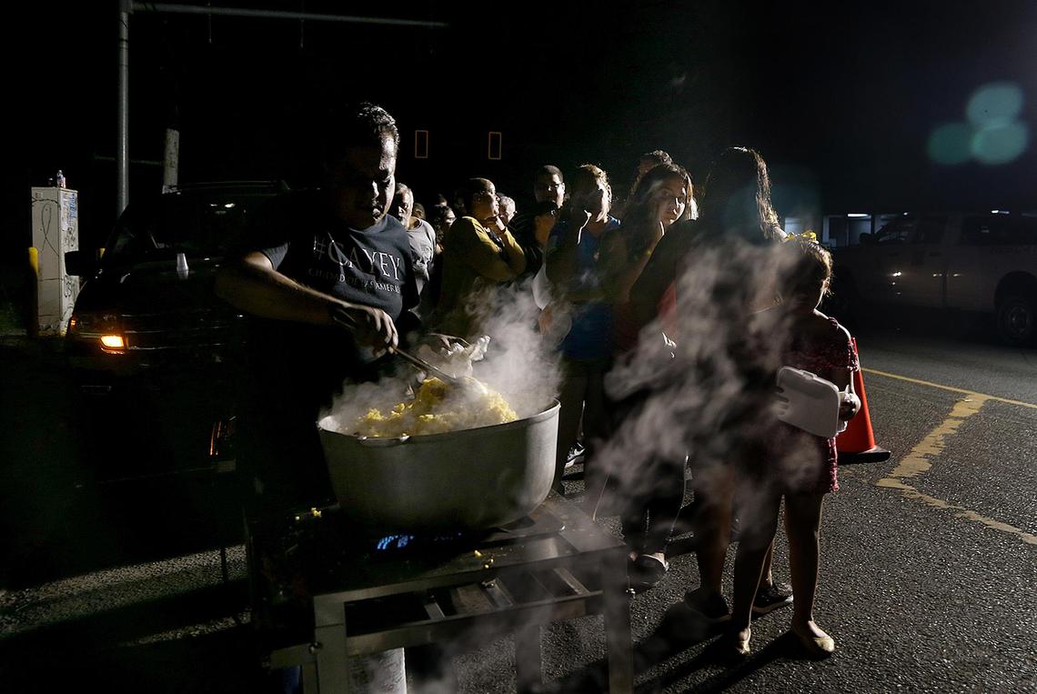 Jose Rosario, a municipal employee cooks for residents of Guayanilla, Puerto Rico, on Wednesday evening as they line up to get hot food provided by the mayor’s office before spending another night sleeping outdoors.