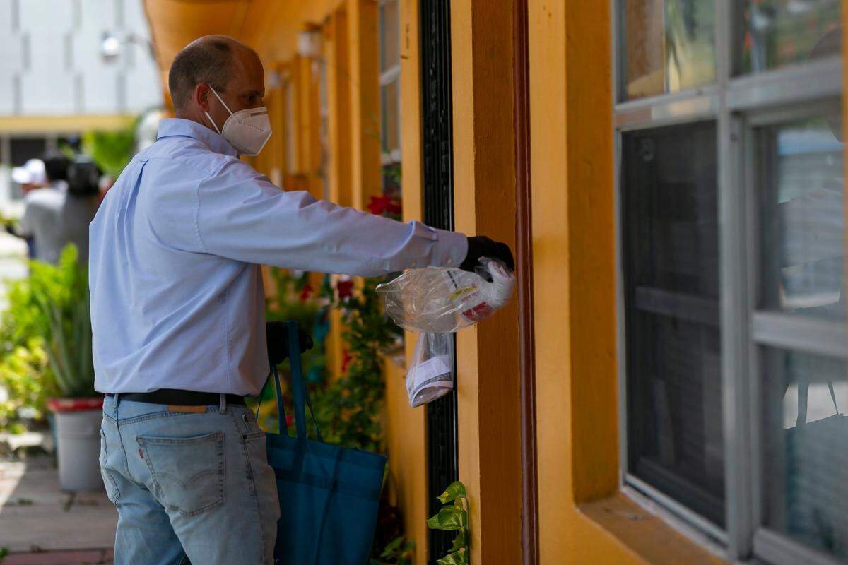 Democratic state Sen. Jose Javier Rodriguez hands out free face masks and COVID-19 informational packets as part of a “rapid response team” canvassing effort in Little Havana, Florida on Saturday, June 27, 2020. County Commissioner Eileen Higgins deployed the team near Little Havana residents who live in coronavirus hotspots.