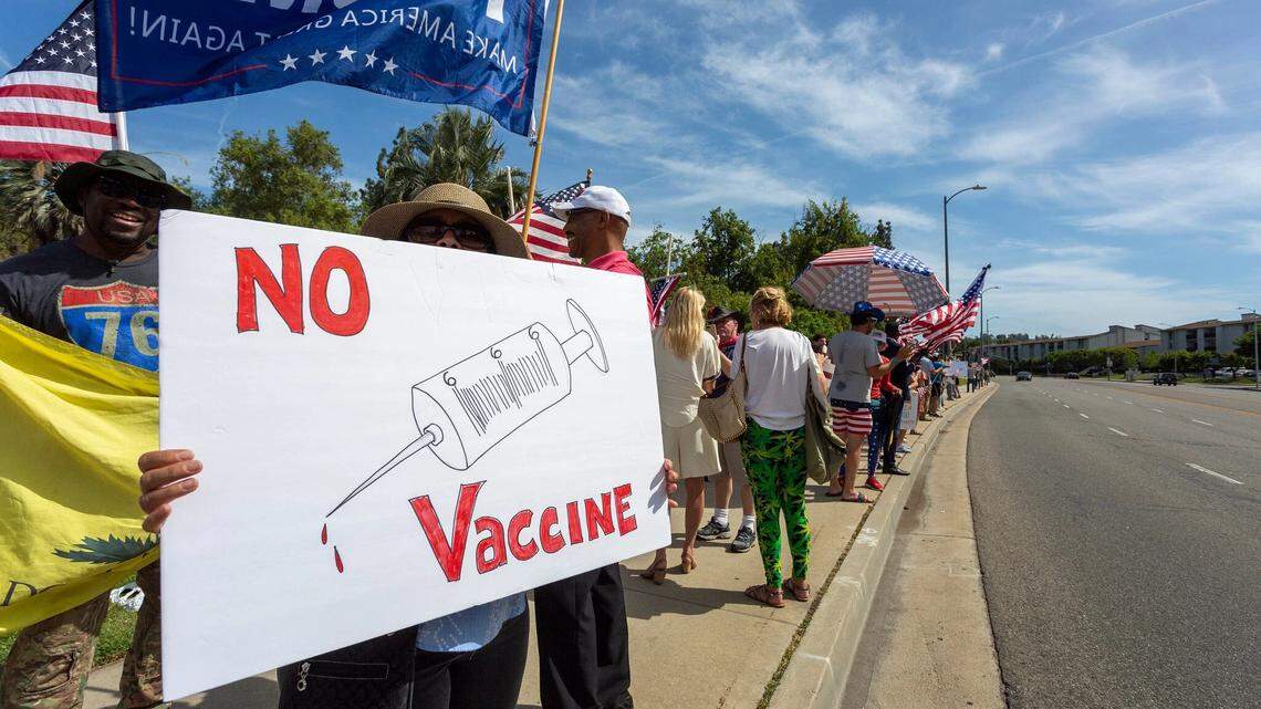 A protester holds an anti-vaccination sign at a pro-Trump rally in May.