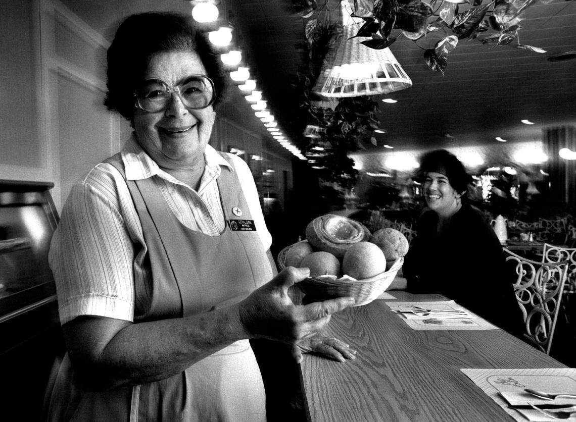Geraldine Roig, a waitress at the Fontainebleau Hotel Coffee shop since 1954. She is shown here holding a basket of buns. At the counter is vacationing Swiss customer Christine Wander.