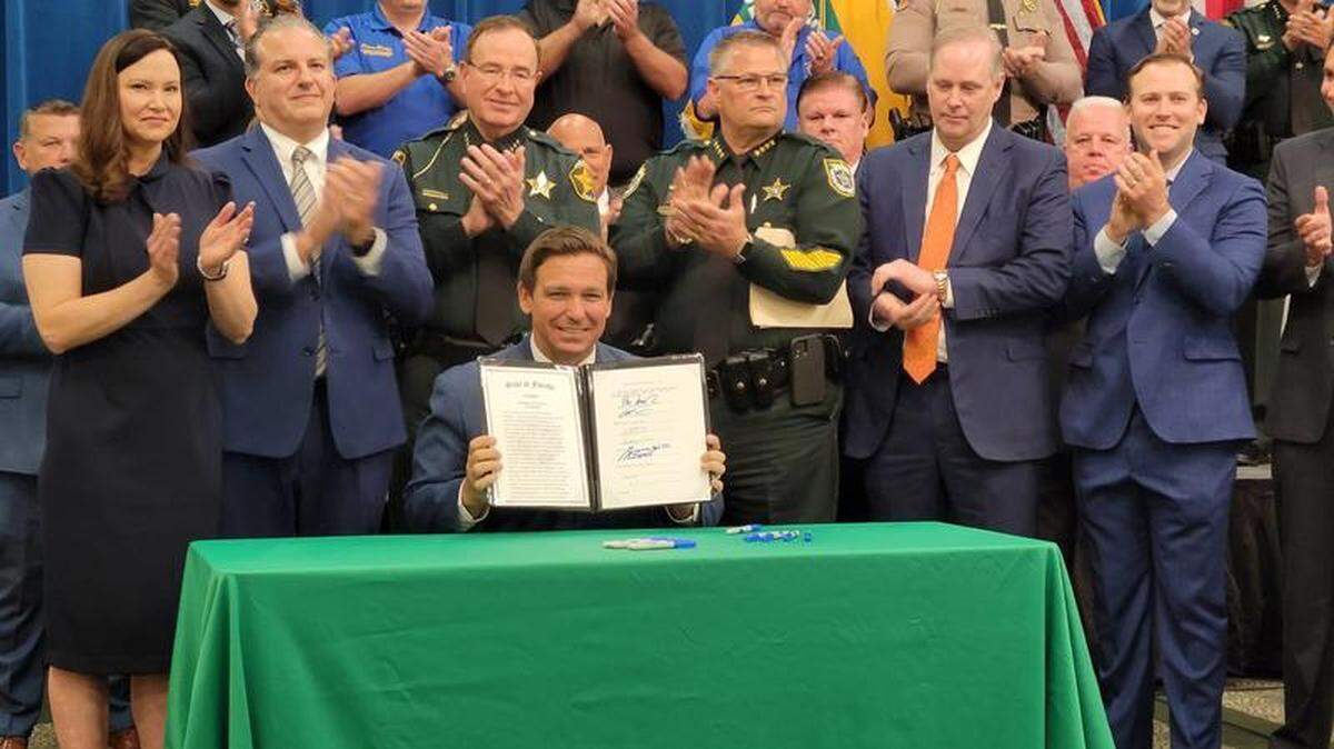 El gobernador Ron DeSantis muestra su firma promulgando el proyecto de ley "antidisturbios".