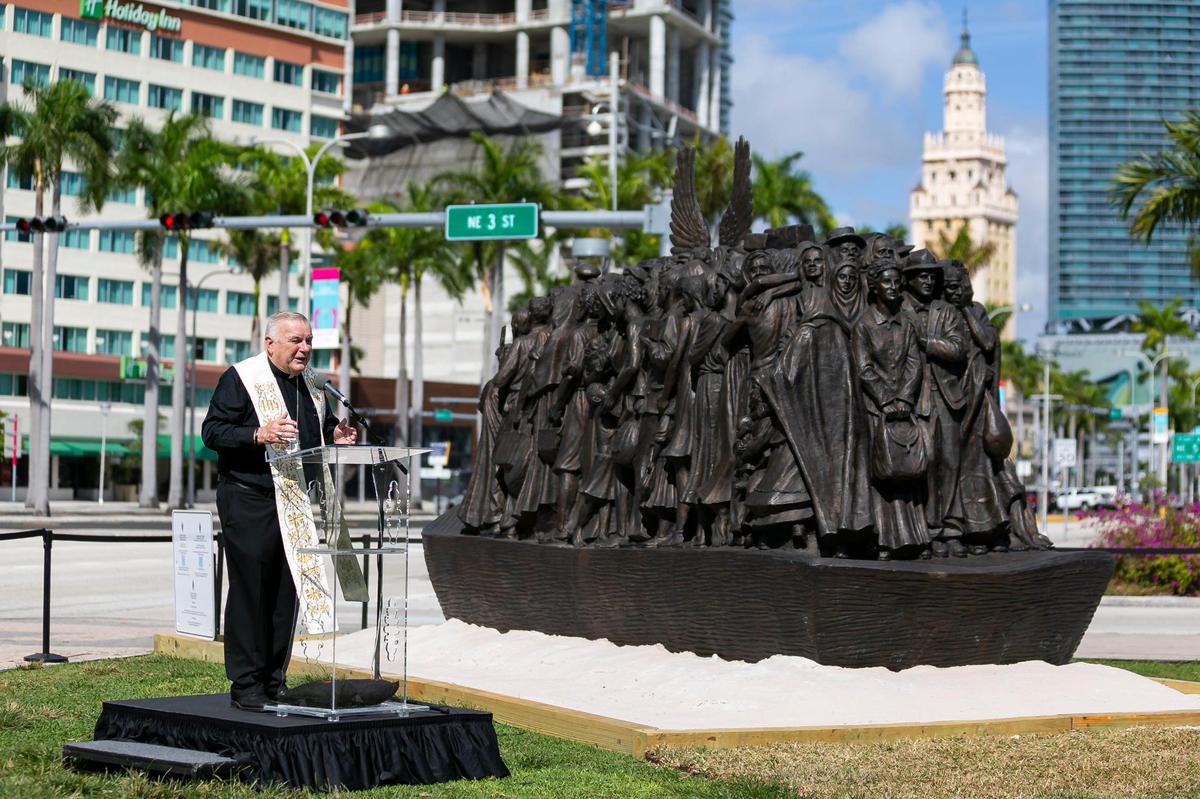 Archbishop Thomas Wenski speaks next to a sculpture titled “Angels Unawares,” at Bayfront Park in downtown Miami on Wednesday, February 10, 2021. The traveling bronze, life-sized sculpture will be open to the public daily for viewing until April 8. The sculpture weighs four tons and is 20-feet long. It features indigenous people, Jews fleeing Nazi Germany, Joseph, Mary, Jesus, and much more.