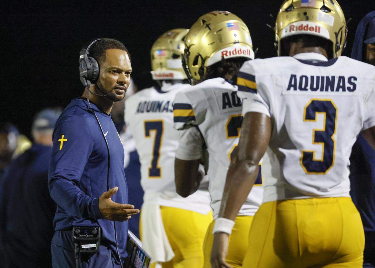 St. Thomas Aquinas head football coach Roger Harriott, greets players on the field after the team scores again in the first half of the game against the Columbus Explorers at Tropical Park Stadium in Miami, Florida, on Friday, September 5, 2025. 