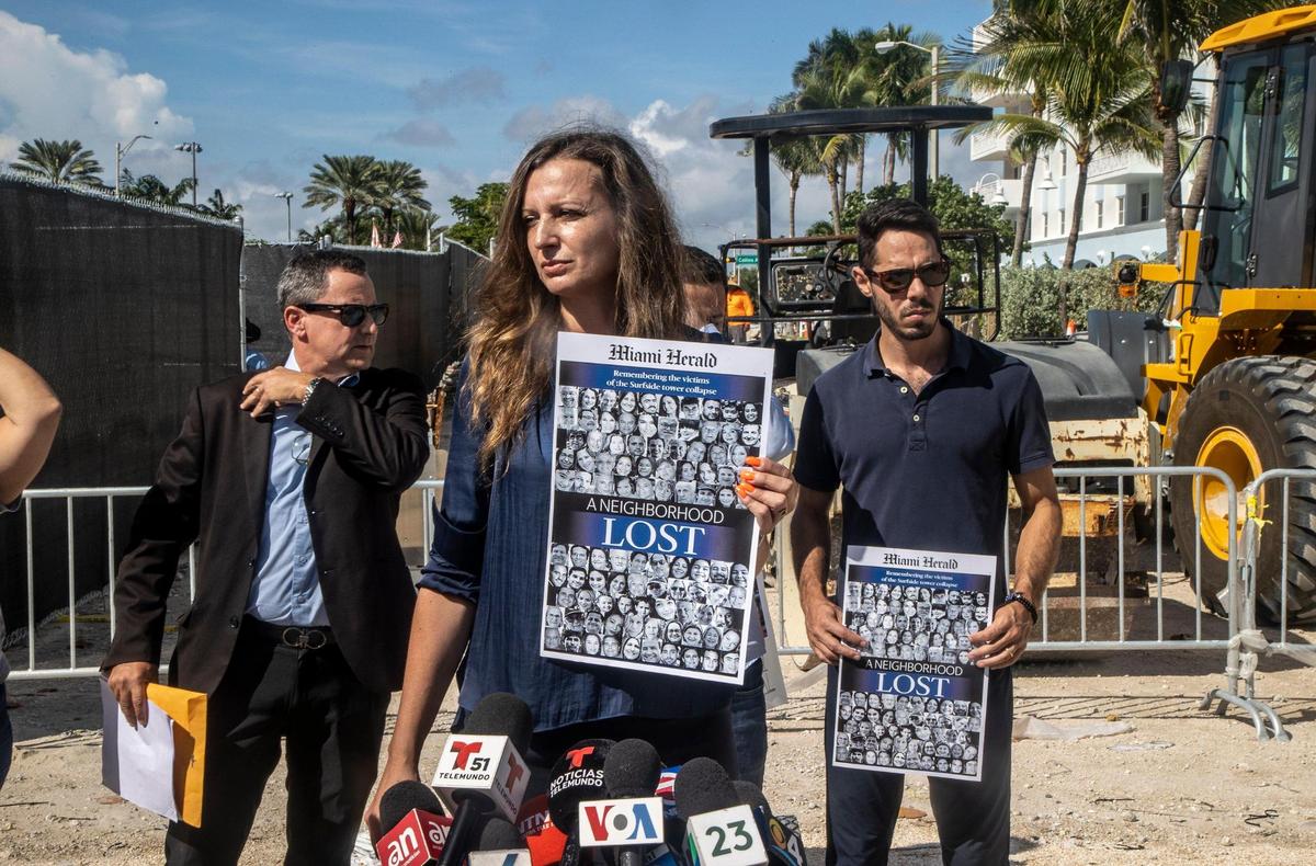 Monica Iken, founder of the September’s Mission foundation, holds a Miami Herald front page as she joins the Langesfeld family at the site of the Champlain Towers South condo collapse, asking that rubble be preserved and a memorial to the 98 victims be built.