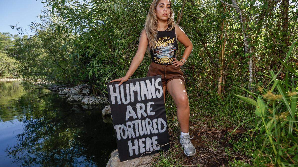 Arianne Betancourt stands in protest in the Everglades outside of Alligator Alcatraz located at the Dade-Collier Training and Transition Airport in the Florida Everglades, Ochopee, Florida, on Friday, May 1, 2026. Her father,  Justo Betancourt, currently being detained at Alligator Alcatraz.