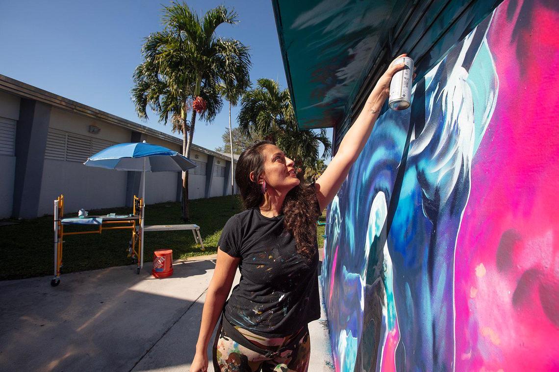 Samara Ash paints “Ascension,” her mural on a wall in Madison Middle School in the West Little River section of Miami.