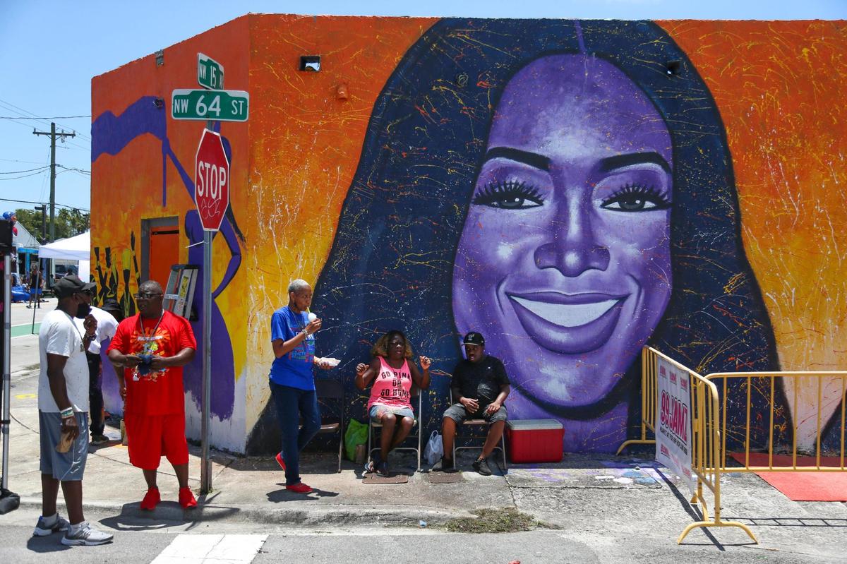People gather on the corner of NW 15th Avenue and 64th Street during a block party where a mural with the portrait of American rapper Katrina Taylor, known as Trina, was painted for Trina Day in Liberty City, Florida, on Saturday, May 14, 2022.
