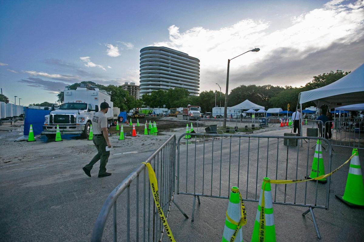 A Miami-Dade police officer walks near the media staging area, just south of where Day 9 of rescue efforts continue at Champlain Towers South, Friday morning, July 2, 2021.
