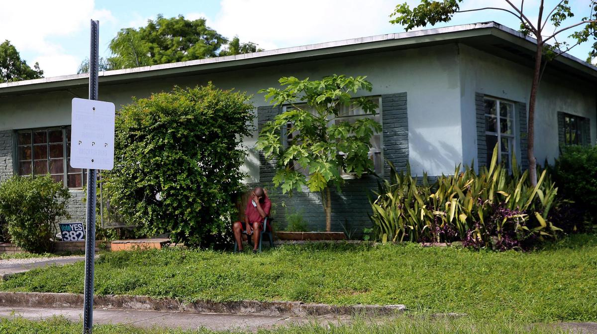 A man sits outside a single-family home that has no hurricane shutters or windows in Little Haiti on Thursday, October 6, 2020.