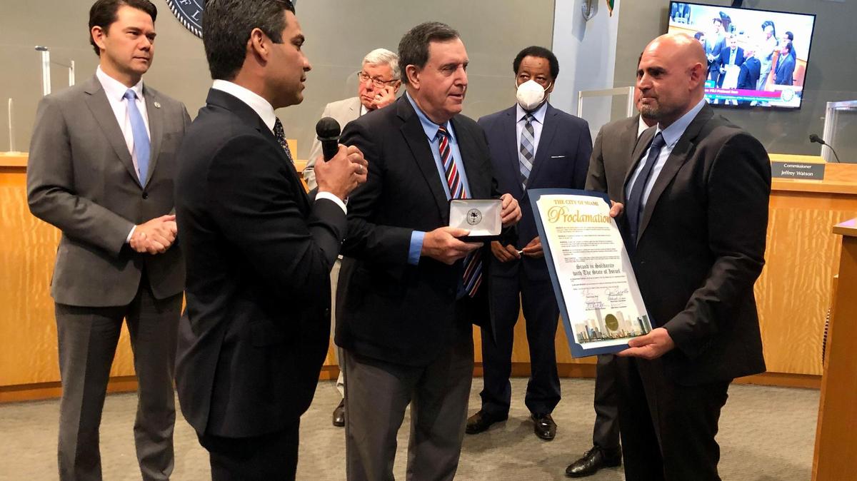 Miami Mayor Francis Suarez, holding the microphone, and Commissioner Joe Carollo, center, present a key to the city of Miami to Maor Elbaz-Starinsky, the newly appointed Israel Consul General to Miami.
