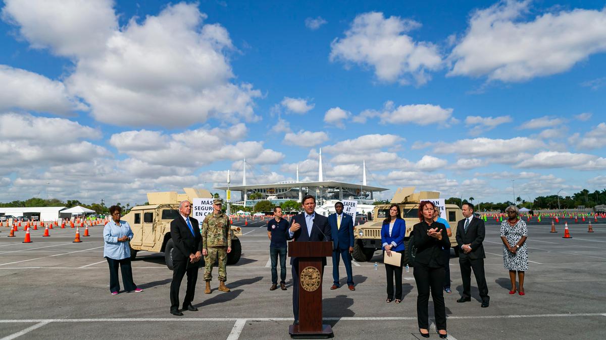 Joined by mayors from Miami-Dade, Broward, Palm Beach and Monroe counties, Florida Gov. Ron DeSantis, center, said during a press conference Monday that he’ll ease restrictions that will allow retired first responders and healthcare workers to return to work.