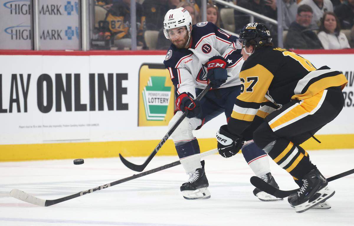 Mar 21, 2025; Pittsburgh, Pennsylvania, USA; Columbus Blue Jackets center Luke Kunin (11) shoots the puck against Pittsburgh Penguins right wing Rickard Rakell (67) during the second period at PPG Paints Arena.