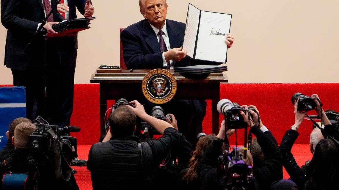 President Donald Trump signs a stack of executive orders at Capital One Arena in Washington on Monday.