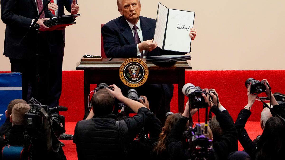 President Donald Trump signs a stack of executive orders at Capital One Arena in Washington on Monday.