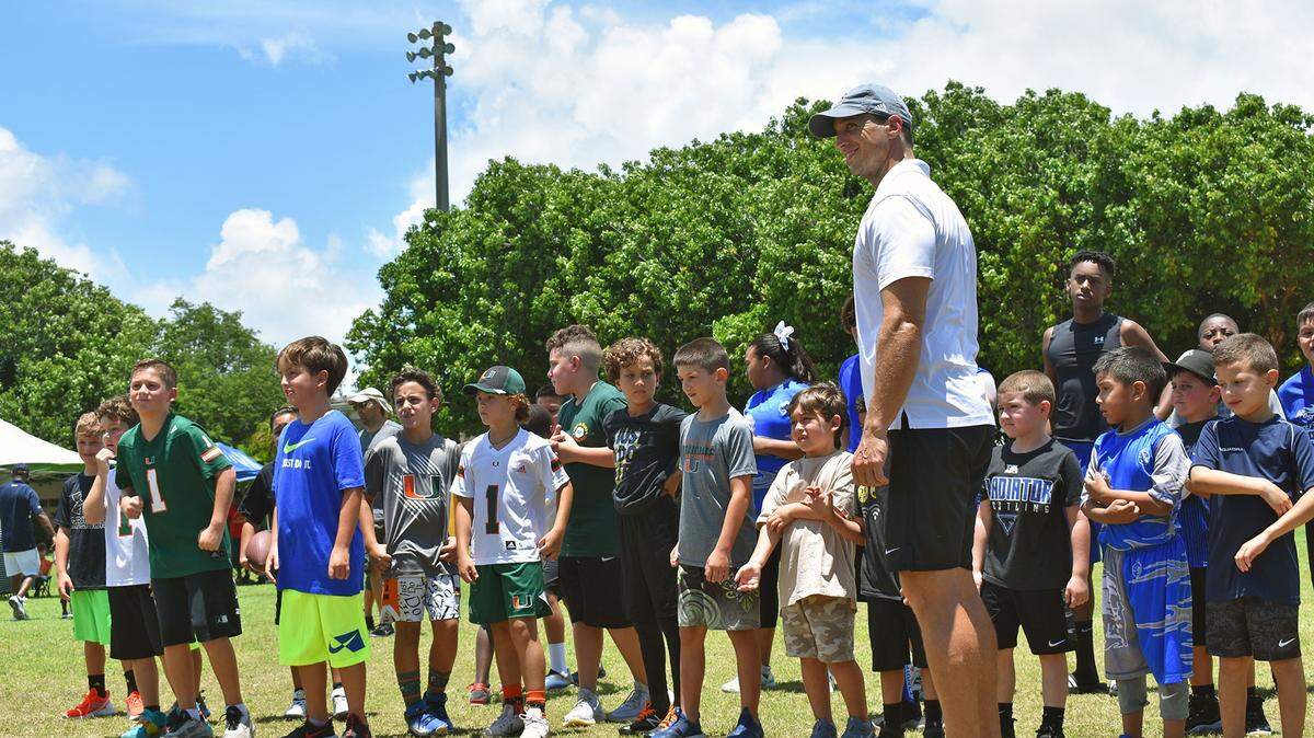 Family Day at the Grey Ghost Youth Football and Cheer League in 2024. Coach Alex Pou, founder of The Home Team, is at right. The Home Team supports the event, which included a guest appearance from the University of Miami football team.
