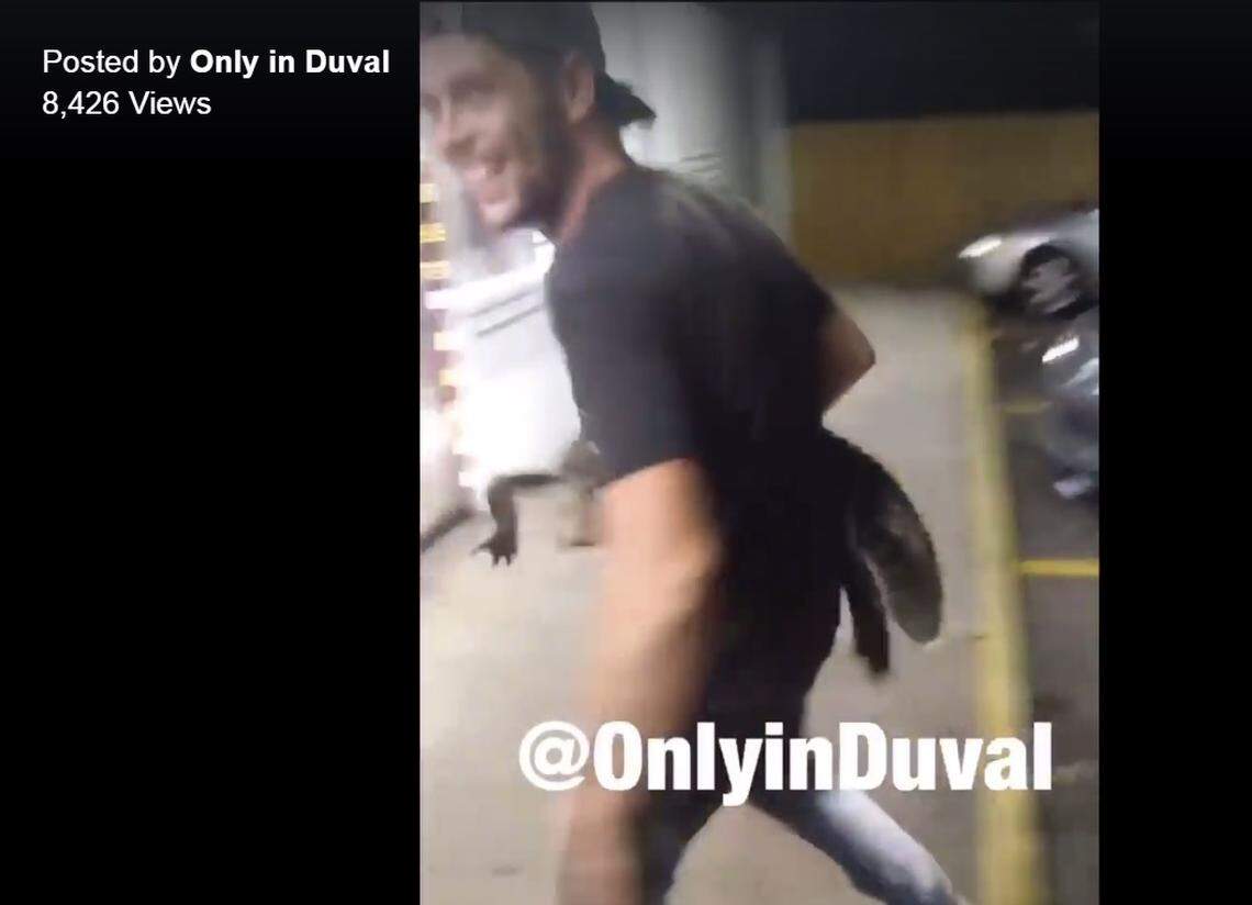 Screen grab from a Facebook video that shows a man entering a Jacksonville convenience store with an alligator under his arm.
