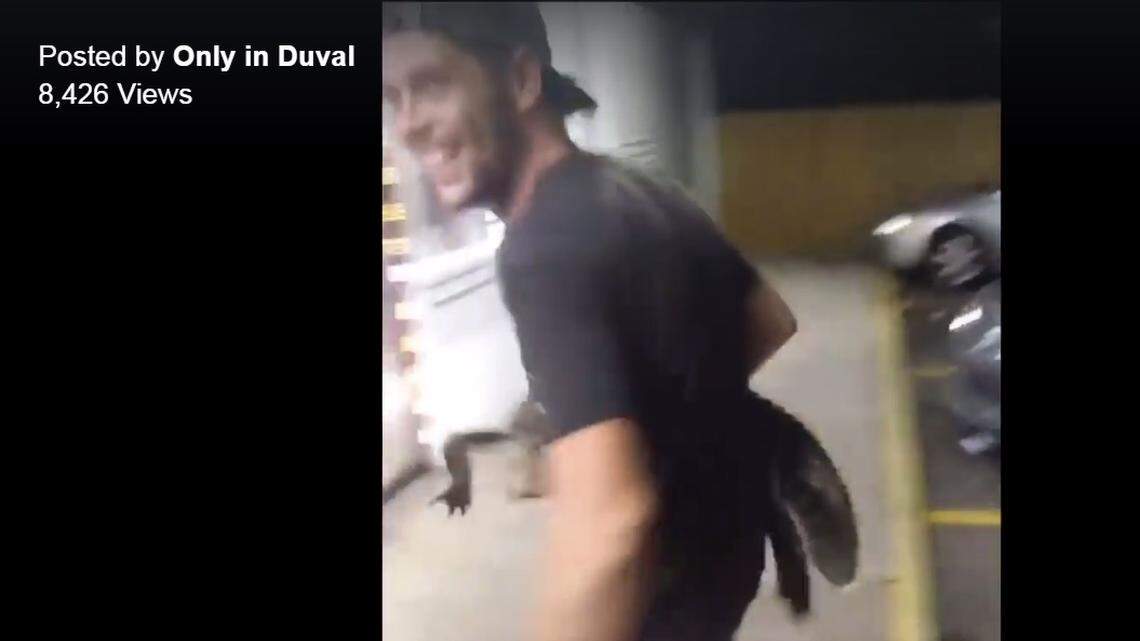 Screen grab from a Facebook video that shows a man entering a Jacksonville convenience store with an alligator under his arm.
