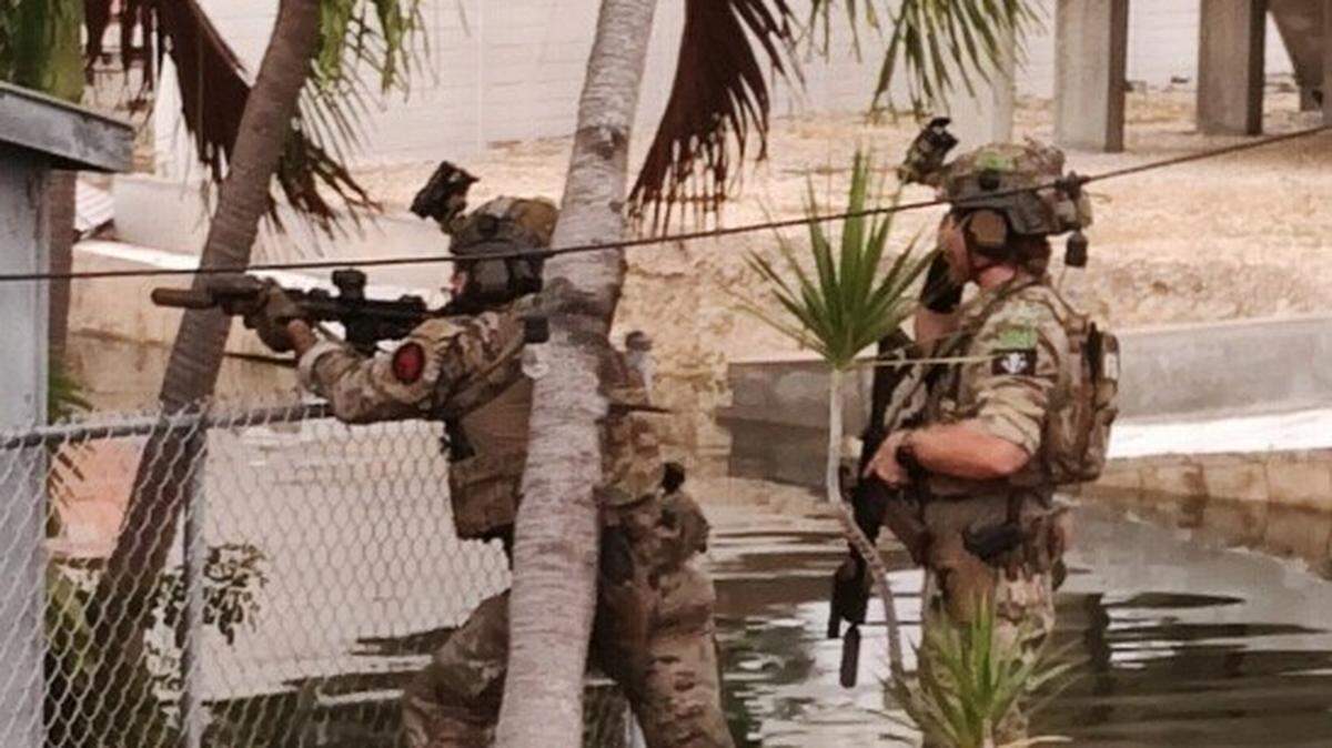 FBI agents armed with semiautomatic rifles prepare to breach a fence in Geiger Key in the Florida Keys Friday, Dec. 16, 2022.