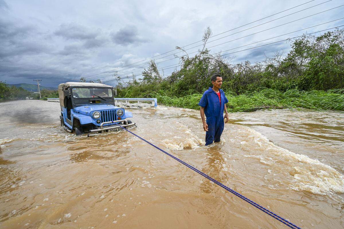A driver tries to remove his vehicle from a flooded area after heavy rains caused by Hurricane Melissa in the town of San Miguel de Parada, Santiago de Cuba province, on October 29, 2025. A powerful Hurricane Melissa made landfall in eastern Cuba on Wednesday, causing damage and flooding to homes and streets in Santiago de Cuba province, an AFP team on the ground reported. 