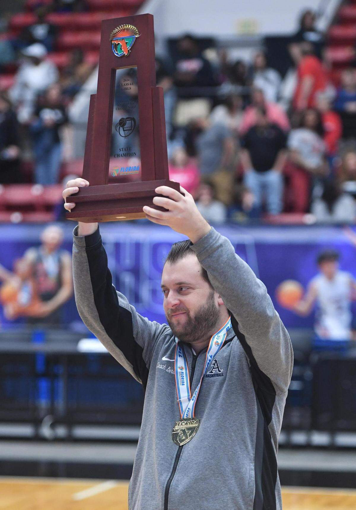St. Thomas Aquinas head coach Oliver Berens raises the State Championship trophy after his team defeated Bloomingdale in the Class 6A final during the Florida High School State Championships at the RP Funding Center in Lakeland, Fl on Friday March 8, 2024. St. Thomas defeated Bloomingdale 70-35. Scott Wheeler | Photo