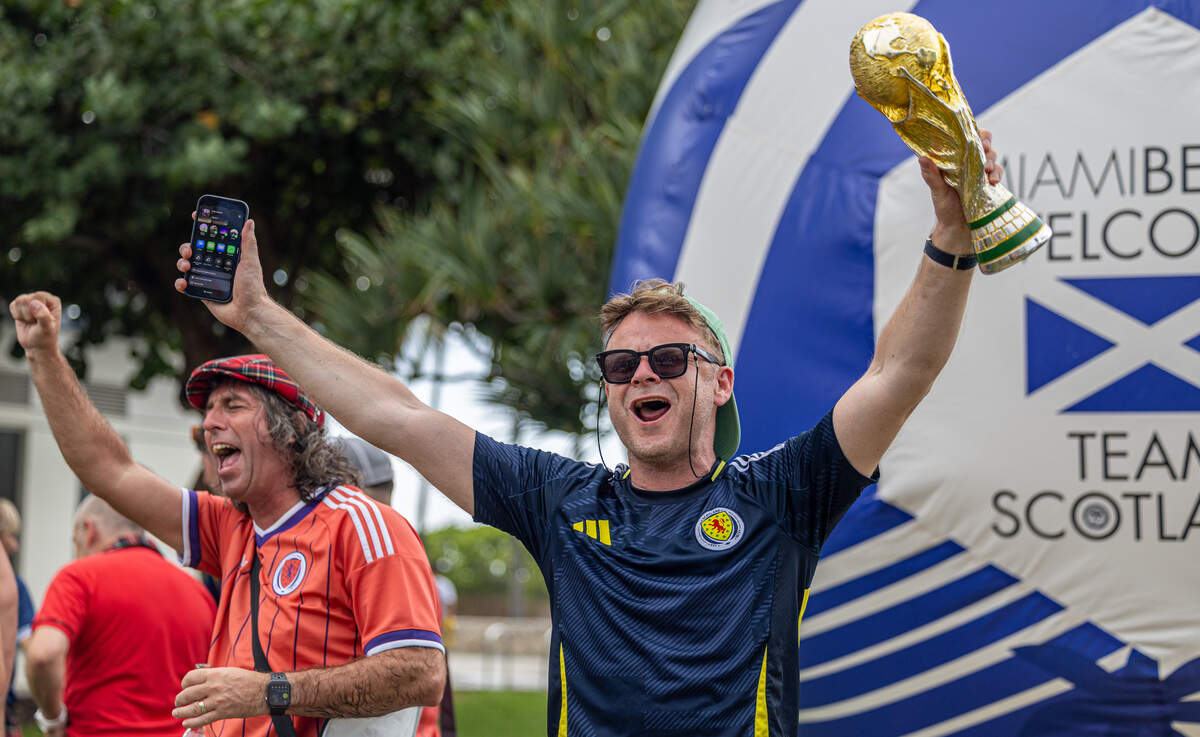 Alex Beattie, right, and Jordan Laird raise their arms during the Tartan Army parade along Ocean Drive in Miami Beach, Fla., on Tuesday, June 23, 2026.