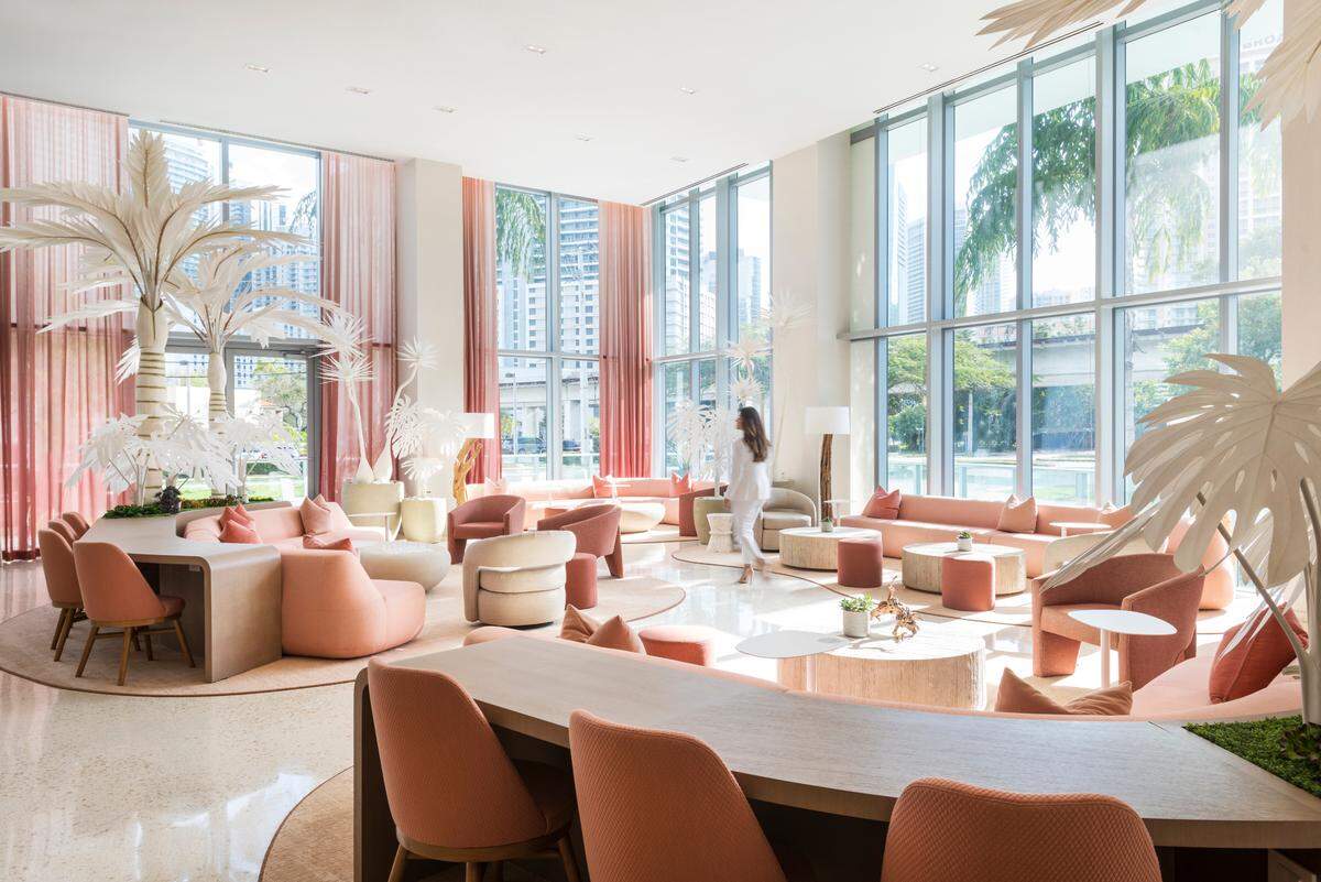 The new hotel lobby features artificial palm trees and blush and beige tones.