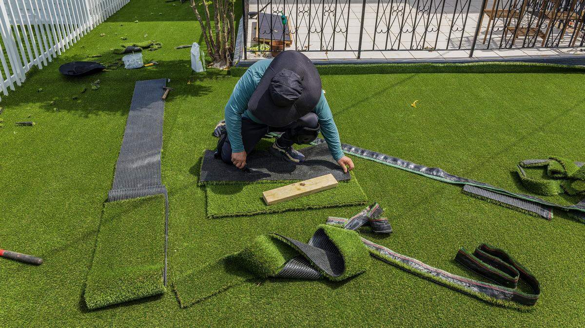 Jerked Ruiz installs some artificial turf in a house in the East Hialeah area, by his brother's company Yoandy Landscaping that specialized in installing this kind of material in high demand in the area, on Tuesday, July 29, 2025.