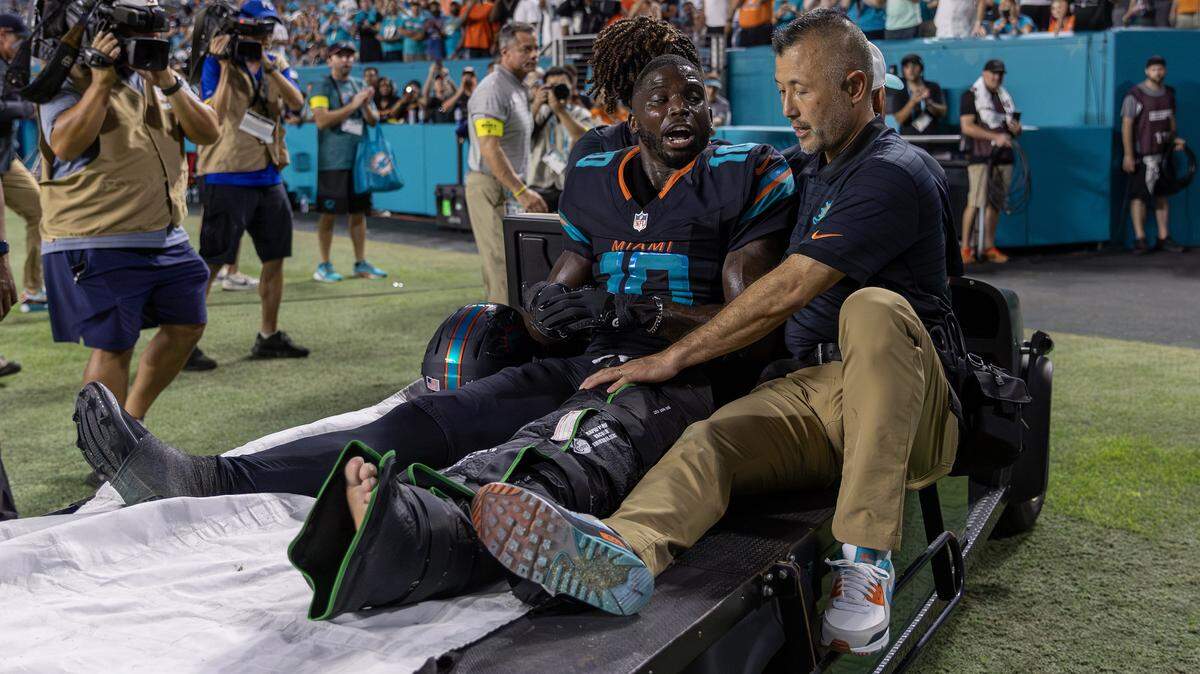 Miami Dolphins wide receiver Tyreek Hill (10) sits next to associate athletic trainer Naohisa Inoue as he is carted off the field after suffering an injury during the second half of an NFL game against the New York Jets at Hard Rock Stadium.