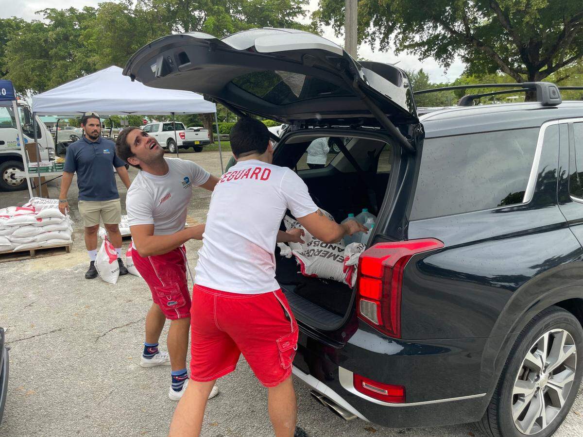 David Campos, left, and Edwardo Grillo, both lifeguards with the Miami-Dade County parks system, load sandbags into a trunk at Tropical Park on Monday, Oct. 7, 2024.