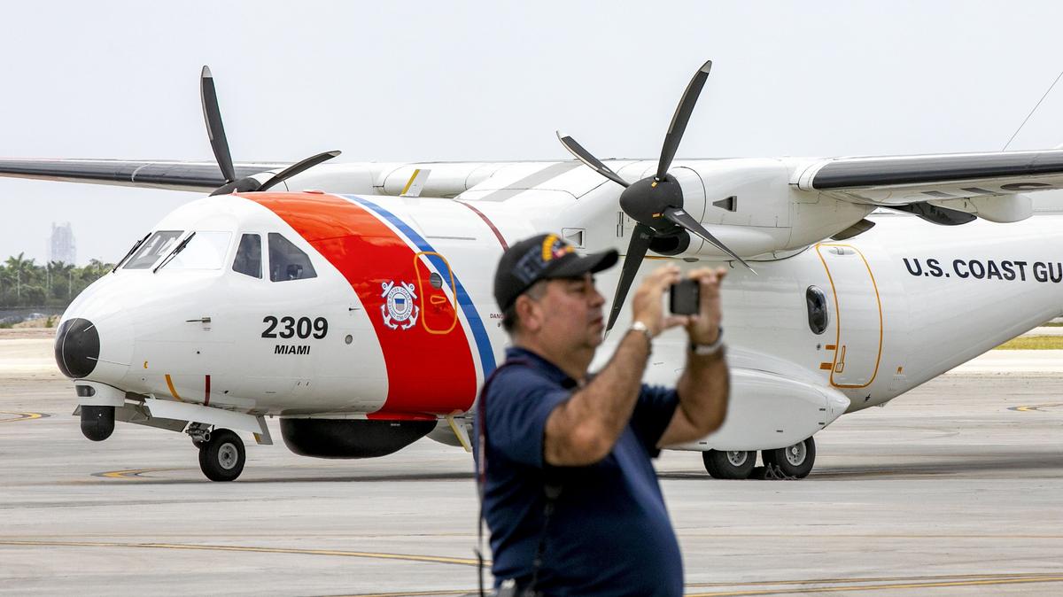A guest stands in front of a U.S. Coast Guard Lockheed HC-130 as he takes a photograph during media day for the 2019 Hyundai Air & Sea Show, at the U.S. Coast Guard Air Station Miami in Opa-Locka, Florida, on Friday, May 24, 2019.