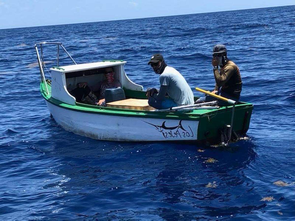 Three people are on board a small fishing boat about 26 miles south of Key West on Thursday, April 28, 2022. The U.S. Coast Guard said they were migrants from Cuba.