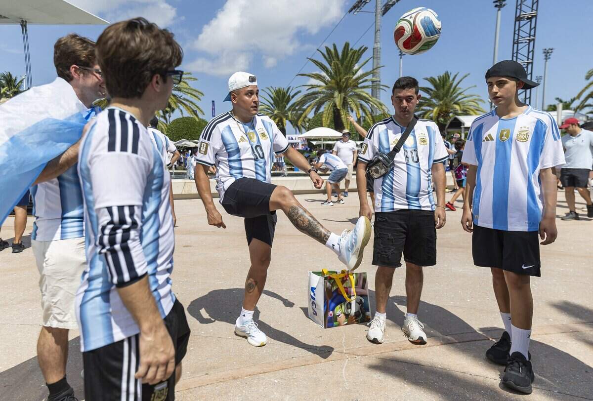 Argentina fan Emanuel Huenulef, center, kicks a soccer ball as he arrives to the Hard Rock Stadium (Miami Stadium) for the FIFA World Cup 2026 Round of 32 soccer match against Cape Verde on Friday, July 3, 2026, in Miami Gardens, Fla.
