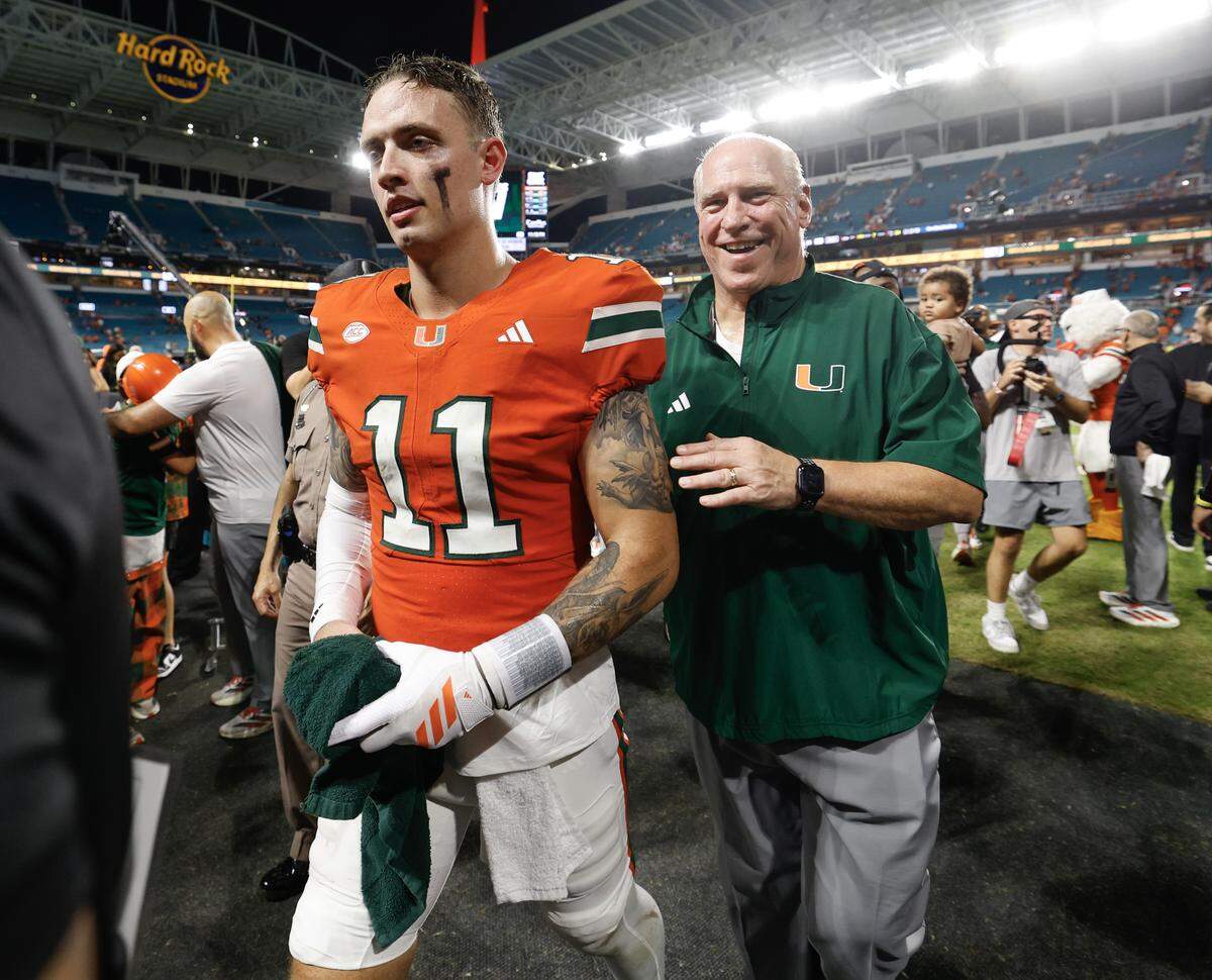 Miami Hurricanes quarterback Carson Beck (11) walks off the field with the head of security and Coral Gables police chief, Ed Hudak, after defeating the Florida Gators during the NCAA football game at Hard Rock Stadium in Miami Gardens, Florida, on Saturday, September 20, 2025.