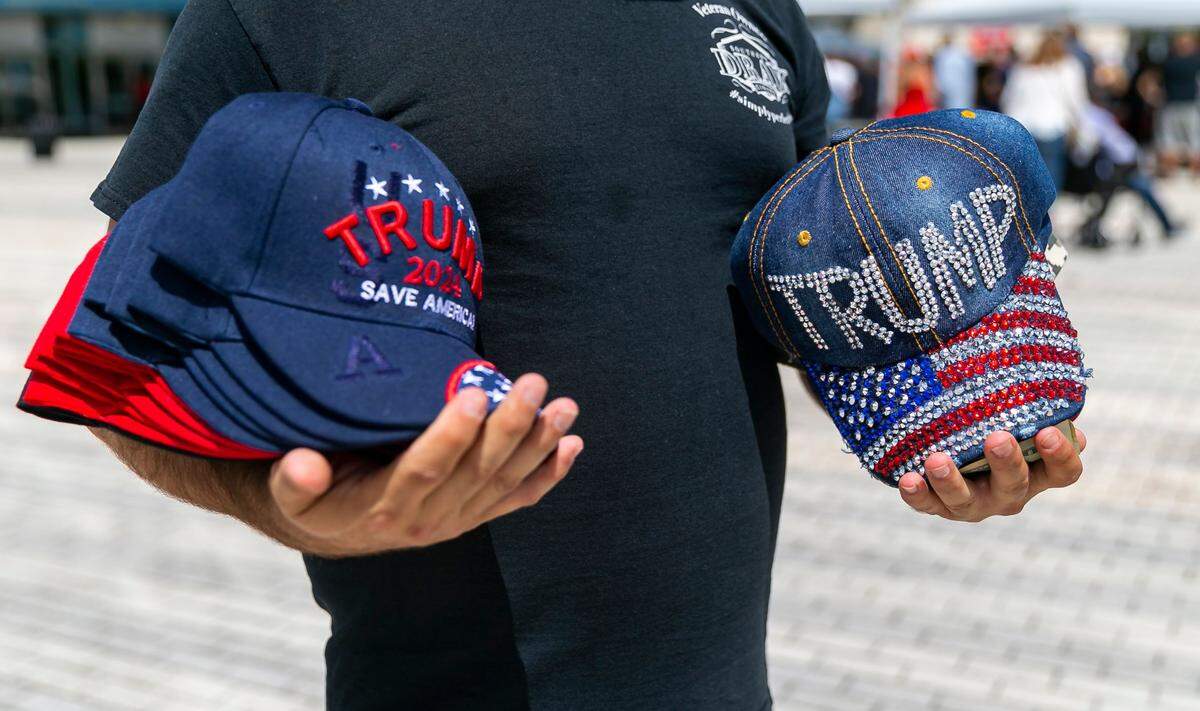 Steven Glazerman sells Donald Trump branded merchandise as people arrive to the American Freedom Tour at the FLA Live Arena in Sunrise, Florida on Saturday, March 19, 2022.