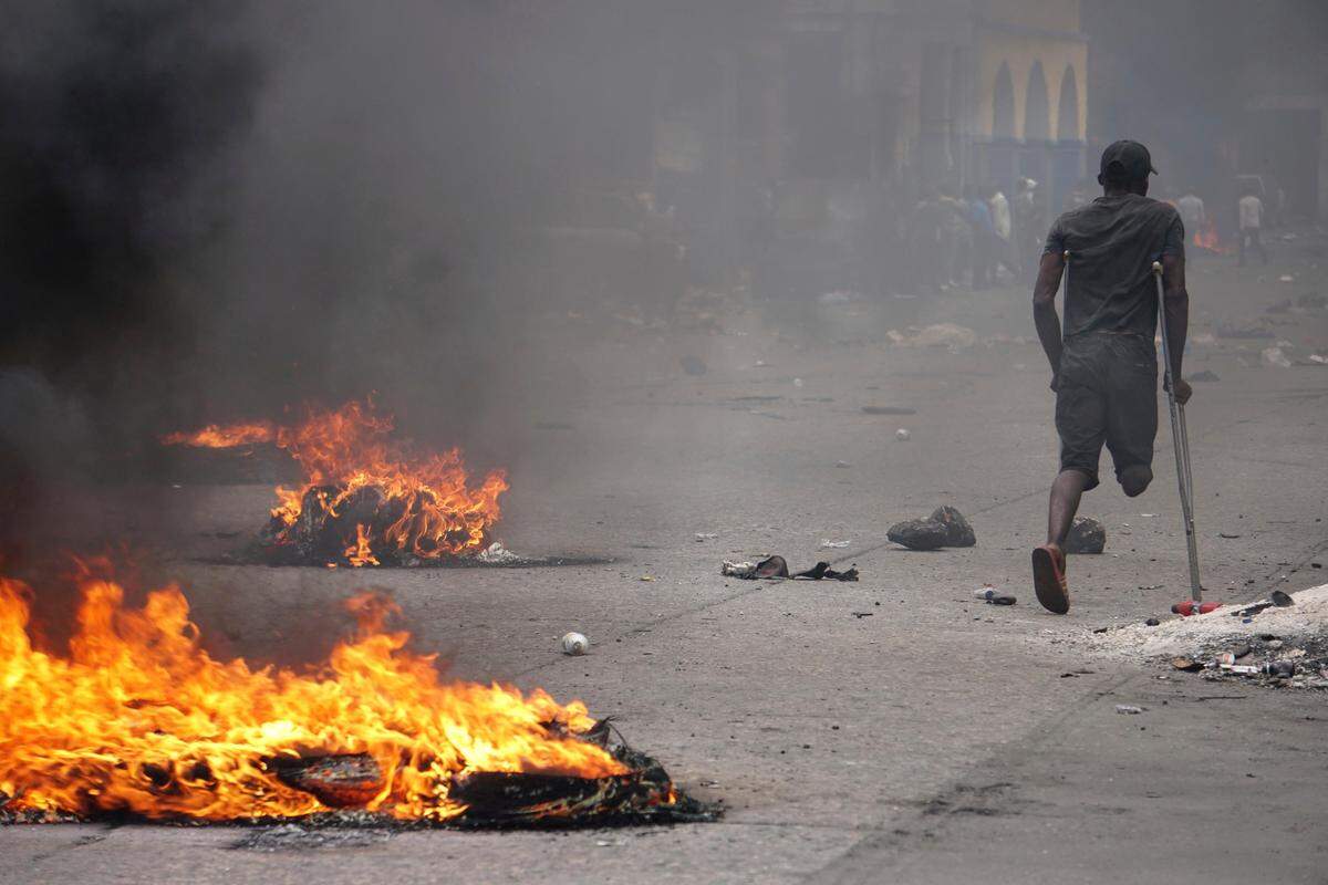 A protester passes burning tires during a demonstration to demand the resignation of President Jovenel Moise in Port-au-Prince, Haiti, Monday, June 10, 2019.