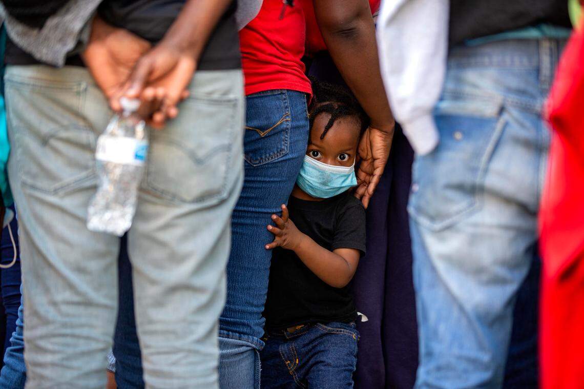A child looks at the camera as Haitians who were deported from the United States line up as they arrive at a hotel where they will be quarantined as a measure against the spread of the new coronavirus, in Tabarre, Haiti, Thursday, April 23, 2020.