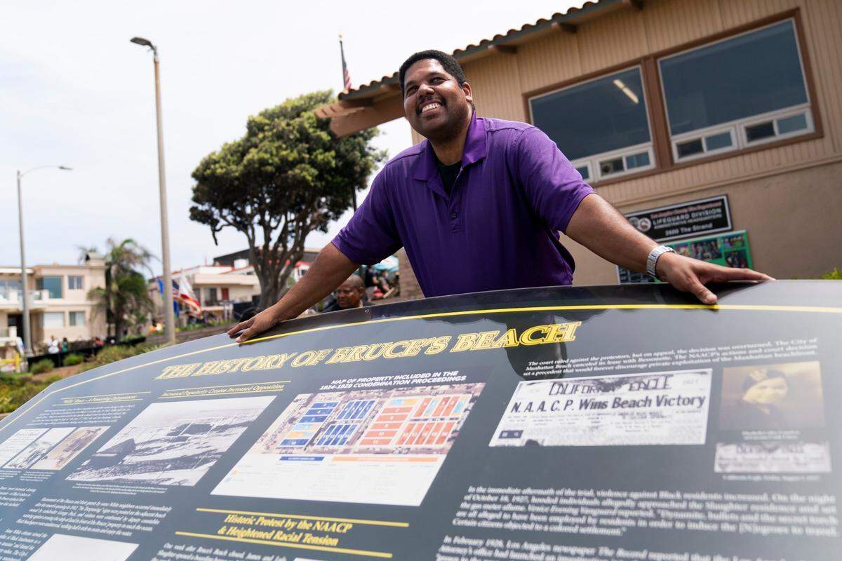 Anthony Bruce, a great-great grandson of Charles and Willa Bruce, poses for photos with a plaque after a dedication ceremony in Manhattan Beach, Calif., Wednesday, July 20, 2022. (AP Photo/Jae C. Hong)