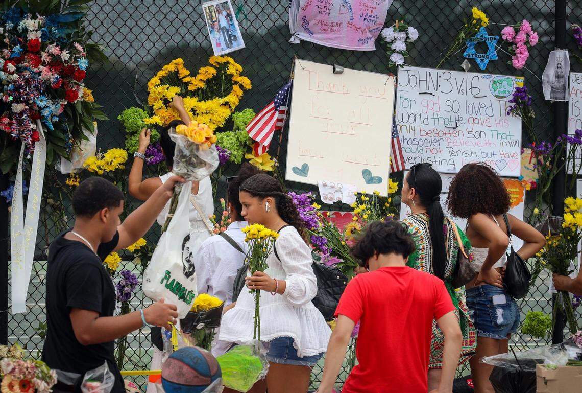 Volunteers along with locals place fresh flowers at the memorial site in Surfside on Tuesday, July 6, 2021, prior to the Guara family’s funeral service blocks away at St. Joseph Catholic Church.