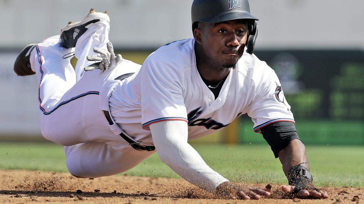 Miami Marlins’ Lewis Brinson dives into third for a stolen base during the third inning of an exhibition spring training baseball game against the St. Louis Cardinals Saturday, Feb. 23, 2019, in Jupiter, Fla. (AP Photo/Jeff Roberson)