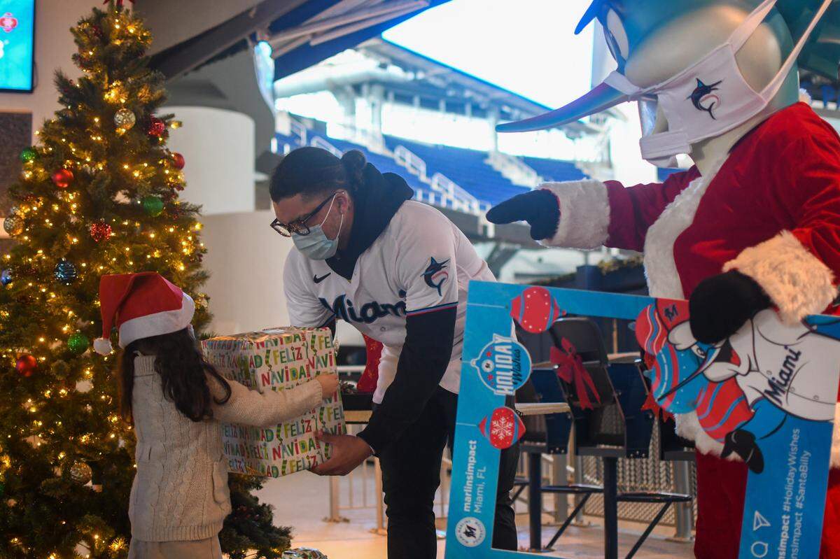 Miami Marlins second baseman Isan Diaz and Billy the Marlin, dressed as Santa Claus, hand out presents to a small group of Pre-K students from CNC on Friday, Dec. 11, 2020, at Marlins Park.