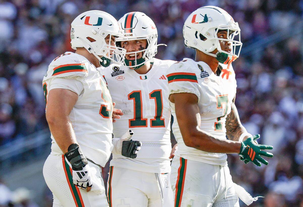 Miami Hurricanes quarterback Carson Beck (11) talks with offensive lineman James Brockermeyer (52) and wide receiver CJ Daniels (7) in the second half of the game against the Texas A&M Aggies during the first round of the 2025 College Football Playoff at Kyle Field at College Station, Texas, on Saturday, December 20, 2025.