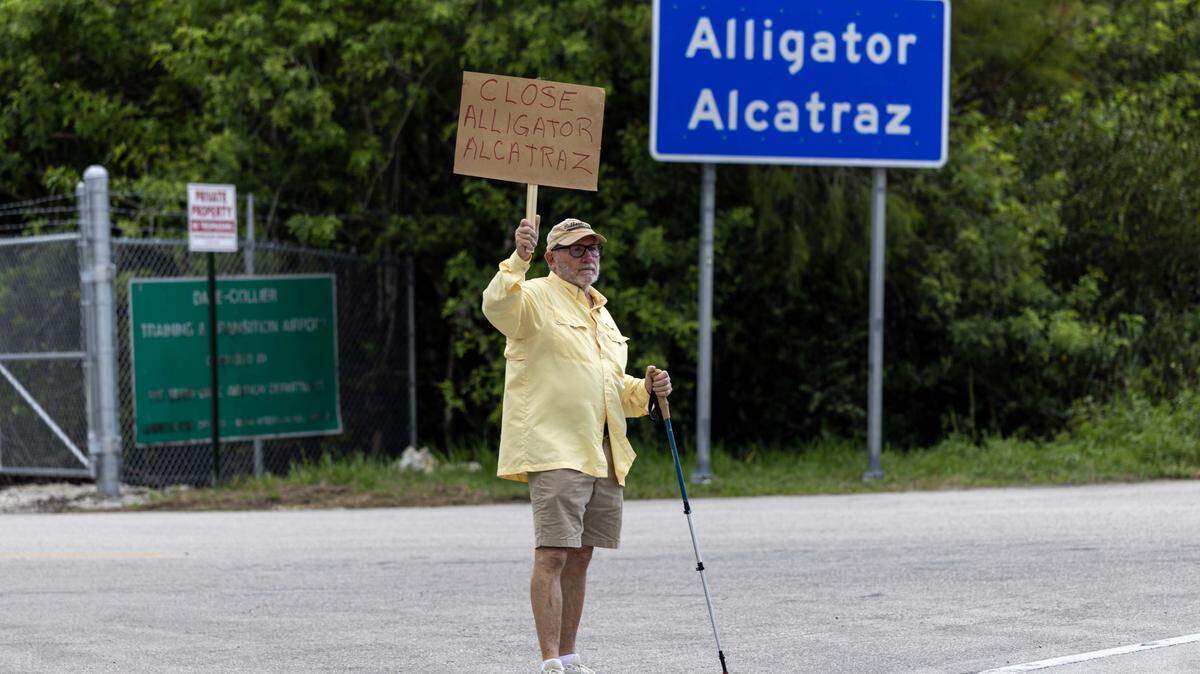Naples resident Bill Hamilton, 73, holds a sign that reads “CLOSE ALLIGATOR ALCATRAZ” after a vigil outside the migrant detention center in the Everglades.