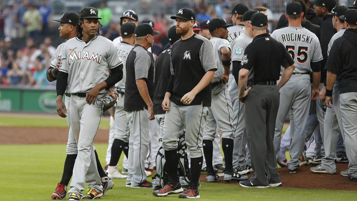Miami Marlins second baseman Starlin Castro (13) holds starting pitcher Jose Urena (62) back as both benches and bullpens empty on to the field after Urena hit Braves Ronald Acuns Jr. with a pitch in the first inning of a baseball game Wednesday, Aug. 15, 2018, in Atlanta. (AP Photo/John Bazemore)