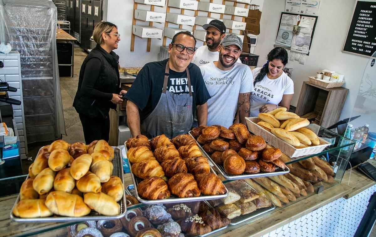 Jesus Brazon, right, and his father, Manuel Brazon, stand behind the counter of their store Caracas Bakery in Doral.