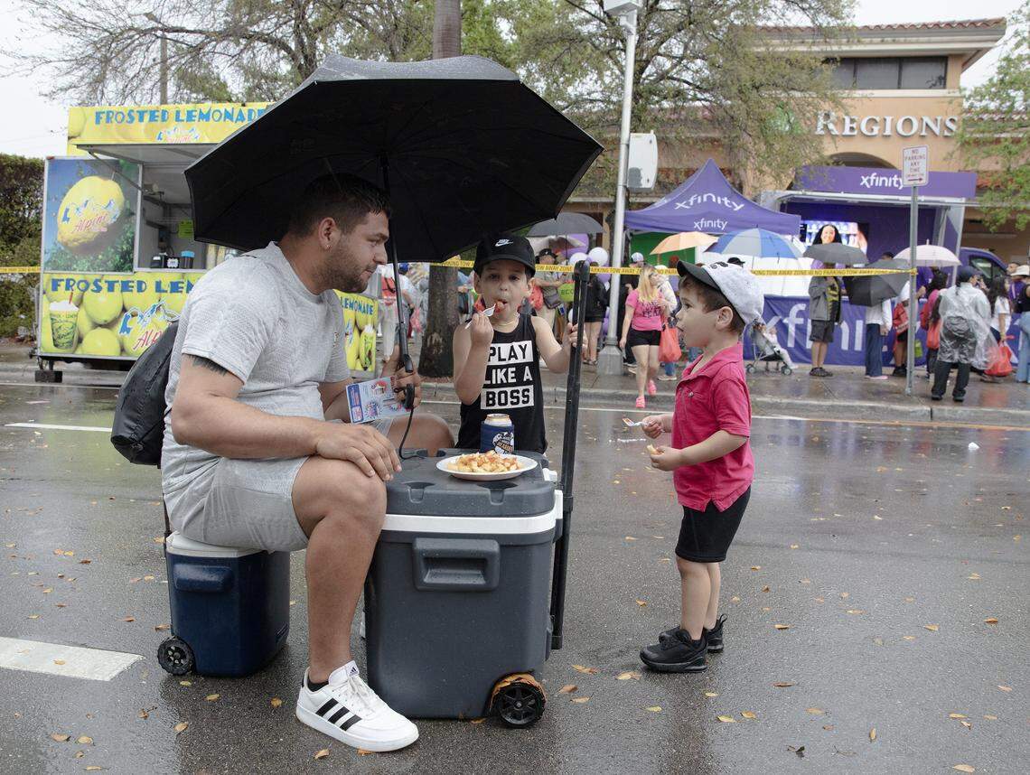 Alejandro Galindo, of Cuba origin, enjoys French Fries with his sons Ethan and Dylan in the middle of SW 8th street during Calle Ocho festival on Sunday, March 15, 2026 in Little Havana. Andrew Uloza / for Miami Herald