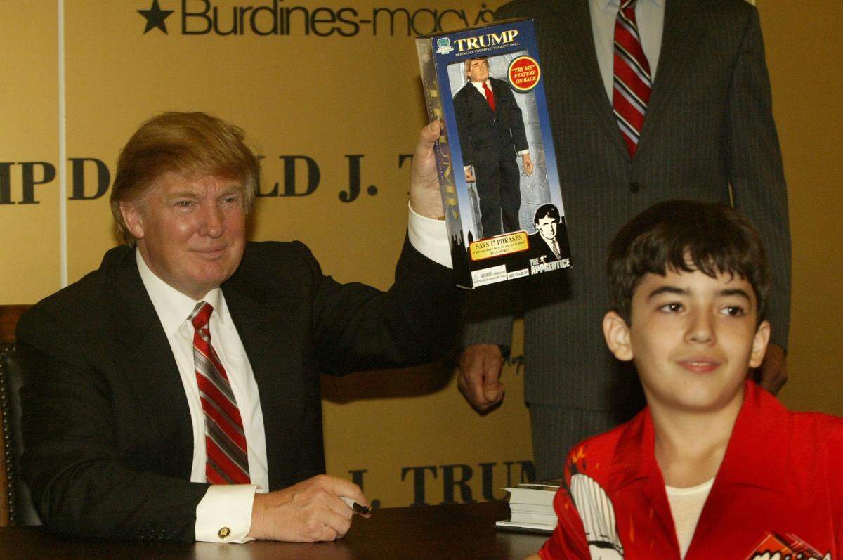 In 2004, Donald Trump holds up an action figure doll of that Nicoli Saunders, 11, brought with him for “The Donald” to sign. Nicoli wants to be like Trump when he grows up. Trump came to Miami to promote his new perfume and line of men’s suits at Burdines in Dadeland Mall.