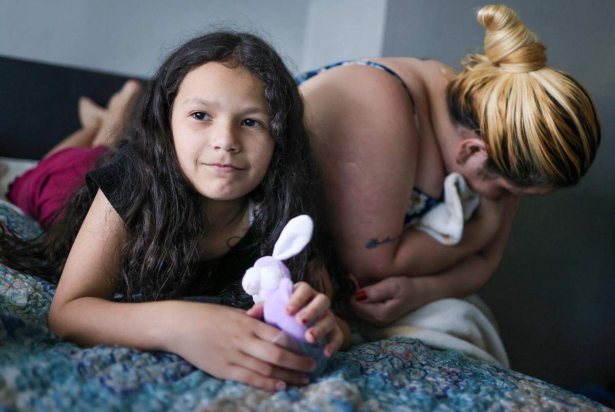 Yelitza Perez, 29, right, leans as her daughter, Paola, 9, left, shares her hope to return back to Venezuela. They are currently staying at Ernesto Motel after an attempt to self-deport stalled when their travel documents were taken at the border several years ago while seeking asylum in the United States on Thursday, April 2, 2026, in Miami, Florida.